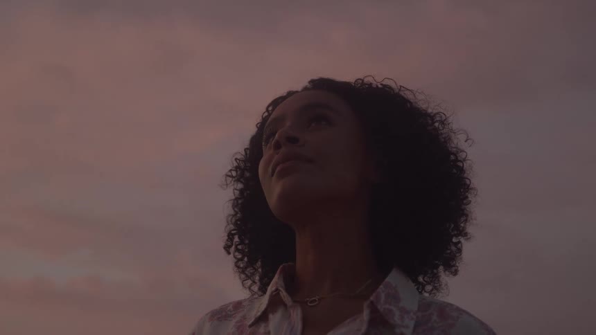 Close up portrait of a young black woman standing outdoors at sunset