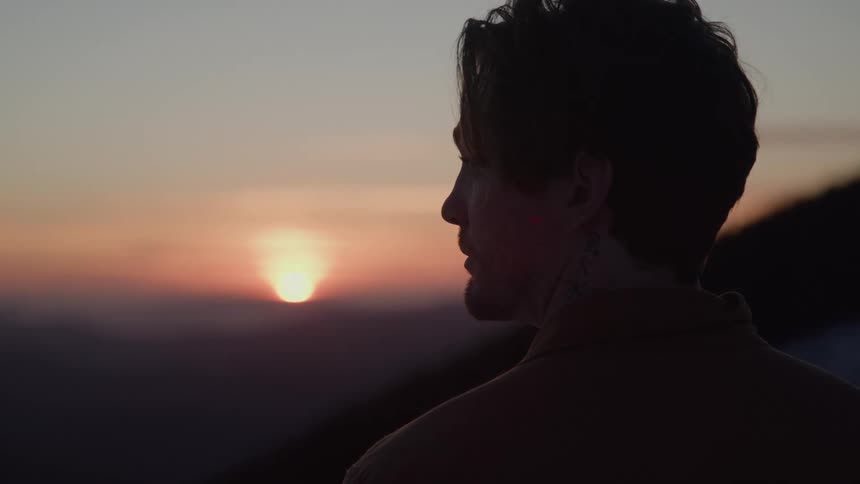 Close up portrait of a young man standing outdoors at sunset