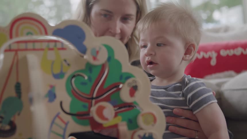 A mother and son play together with toys in the living room