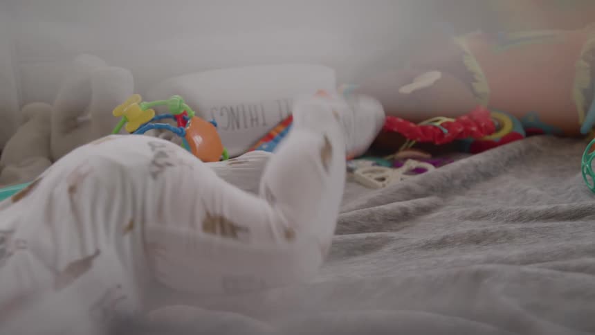 Close up of a male baby crawling and moving with their abdomen across a room floor during daytime