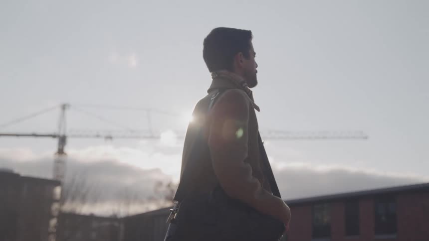 Close up portrait of a young man standing outdoors in a city during daytime