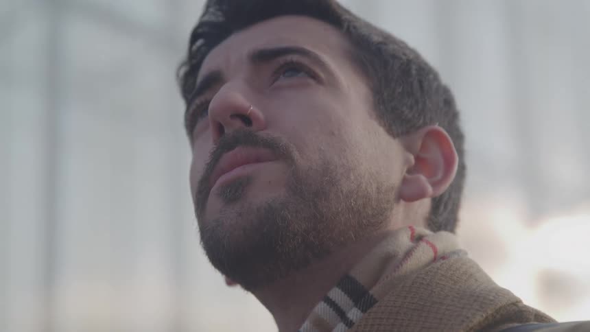 A man looks up toward the sky with a contemplative expression