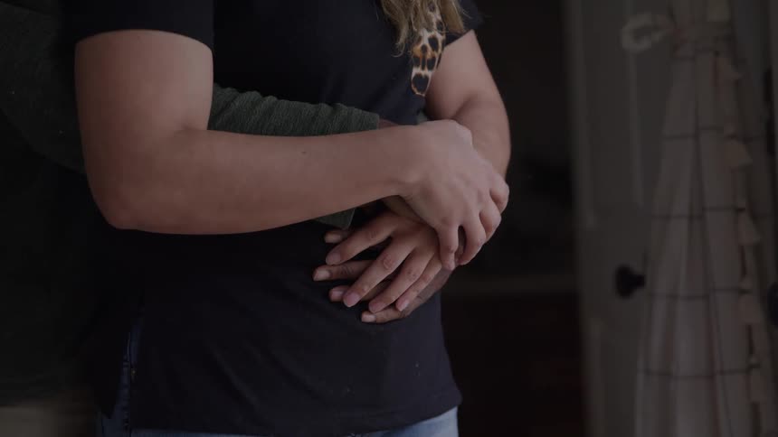 A man and a woman in a close embrace are seen with his arm wrapped around her waist