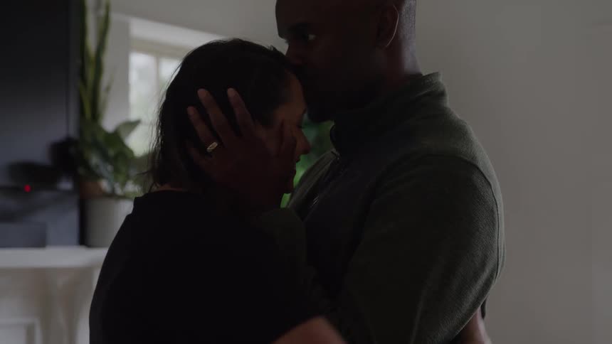 A couple hug and kiss while they dance at home