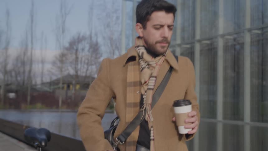 Man walking outdoors with a disposable coffee cup
