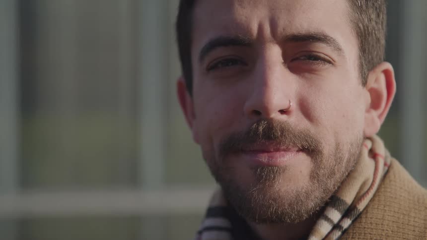 A man looking away from the camera and then turns and looks at the camera and smiles