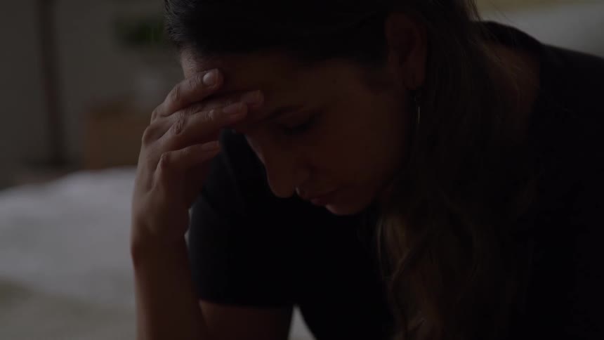 Woman with her head down and her hand on her forehead