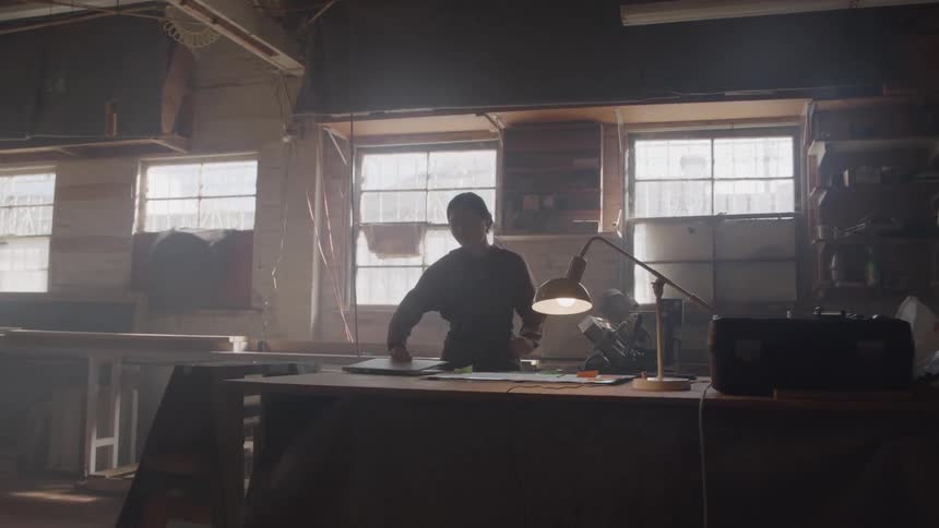 Woman working on a laptop in a workshop lit by natural light