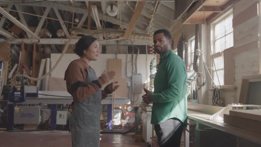 Man and a woman are talking inside a factory