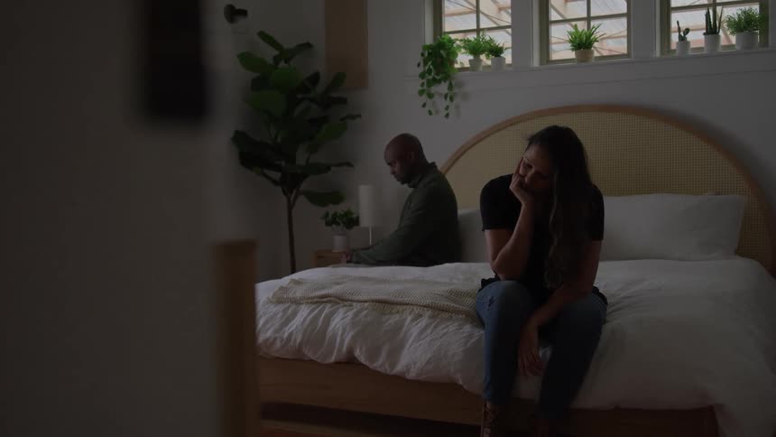 Woman sitting on bed with a dejected expression