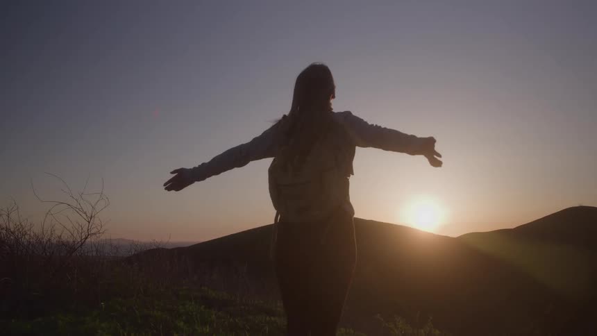 The woman watches the sunrise by the mountains