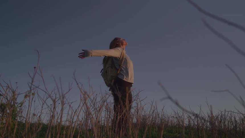 A woman stands outdoors with a backpack