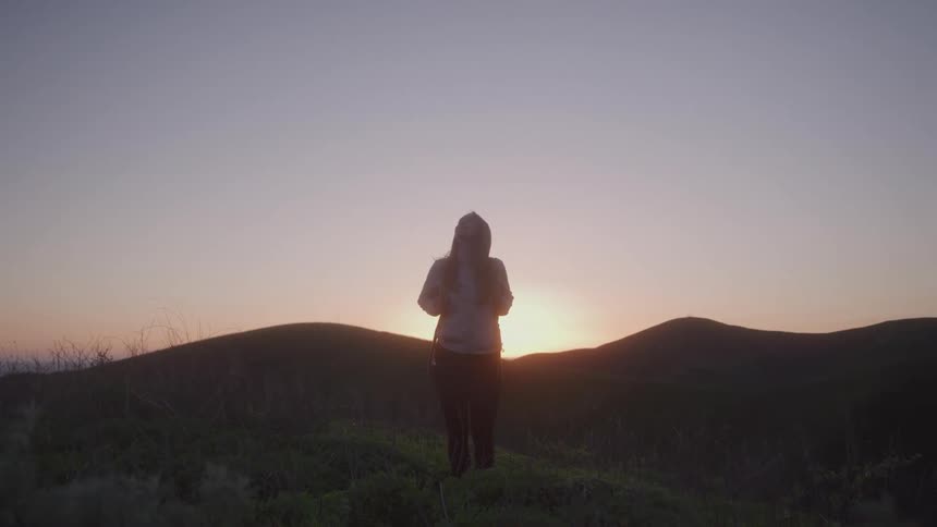 Wind blows the womans hair at sunrise