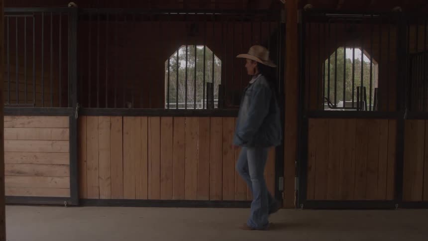 The woman walks past the stables