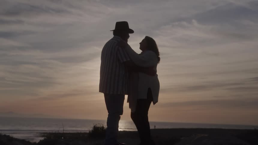 Couple embracing by the sea during sunset