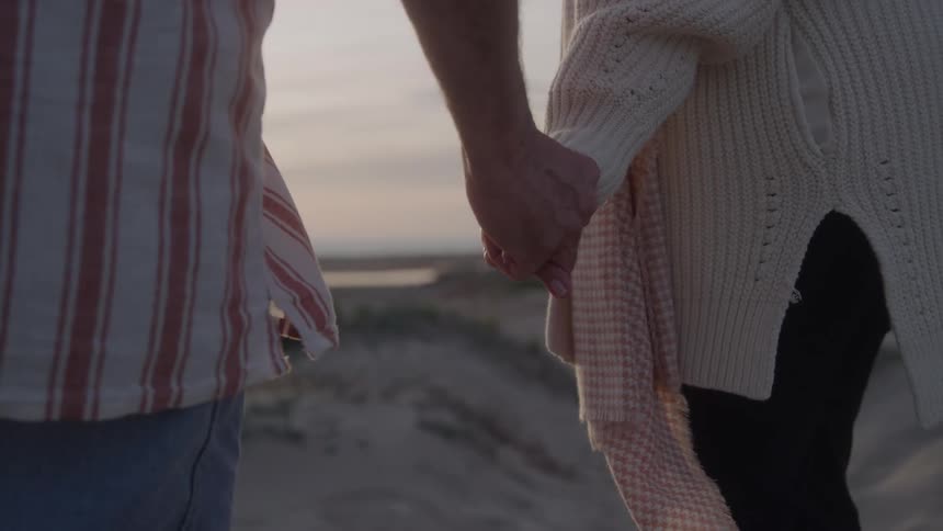 Couple walks hand in hand at sunset