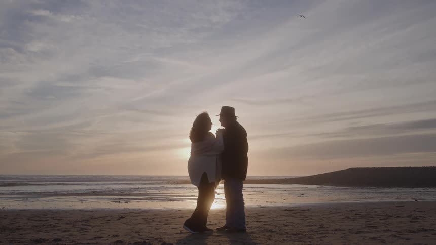 Couple facing each other on the beach at sunset