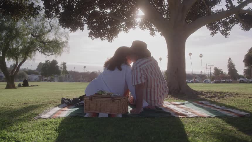 A couple sits on a blanket together while having a picnic