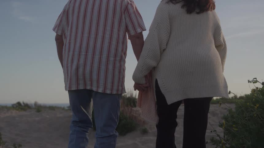 Couple walks hand in hand along an outdoor trail