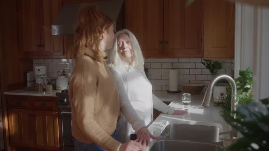 Two women hugging in the kitchen near the sink