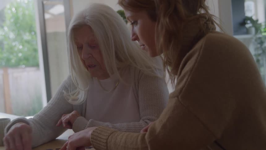 Two women assemble a puzzle together at a table