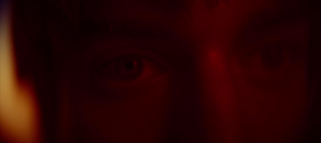 A man blinks while looking at a red light