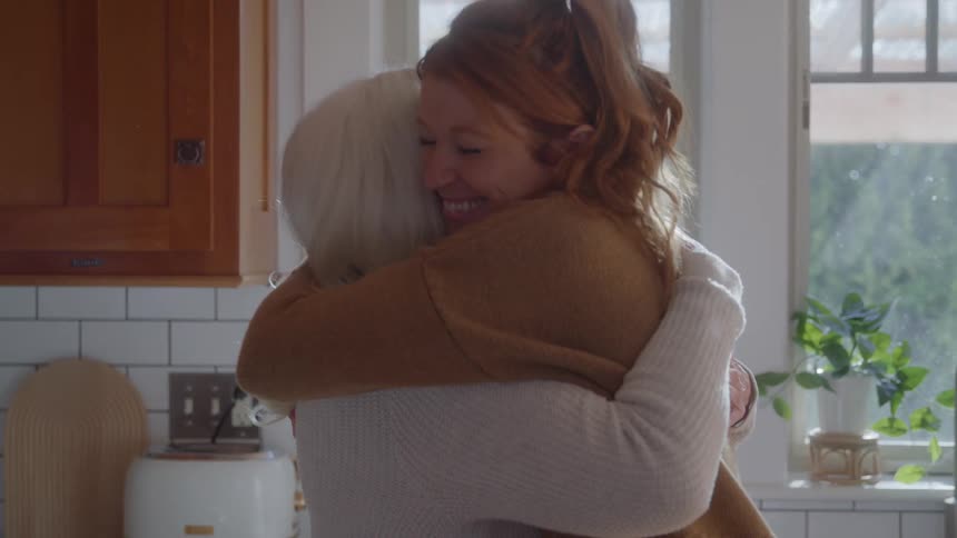 Mother and daughter hugging in the kitchen