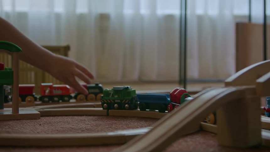 Child plays with a colorful wooden toy train on tracks