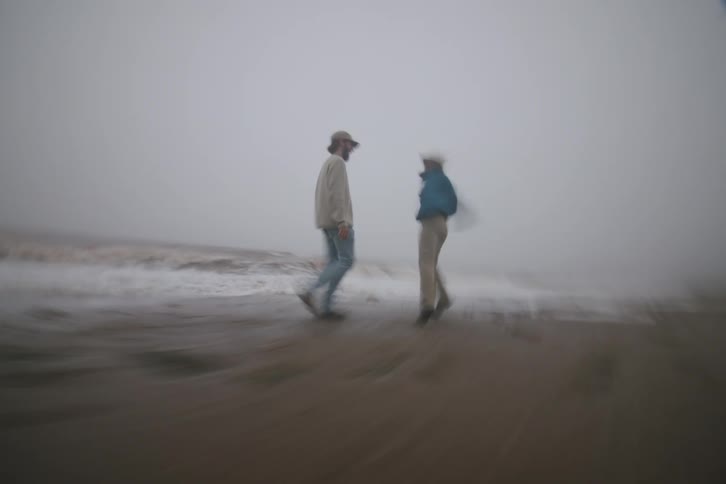 Two people walk and play by the seaside in the mist