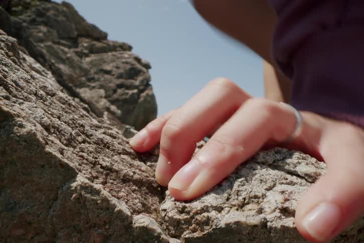 Hand with a ring gripping rock while climbing