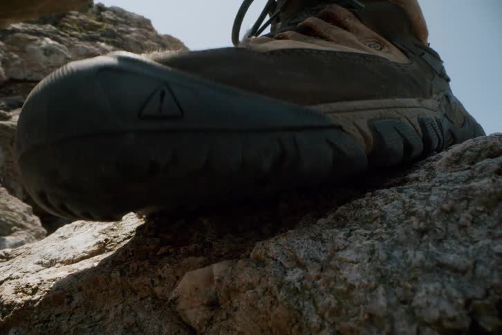 Person wearing boots climbing over rocks