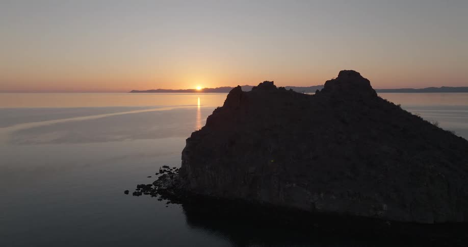 Dark rocky formation facing the sea at sunset