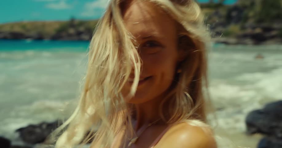 The woman smiles and tosses her hair on the beach