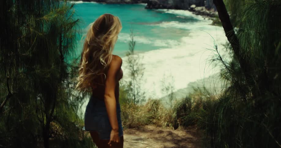 A woman walks toward the beach next to the ocean