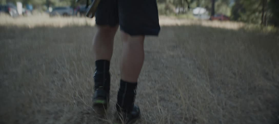 A person walking through dry grass in rugged boots