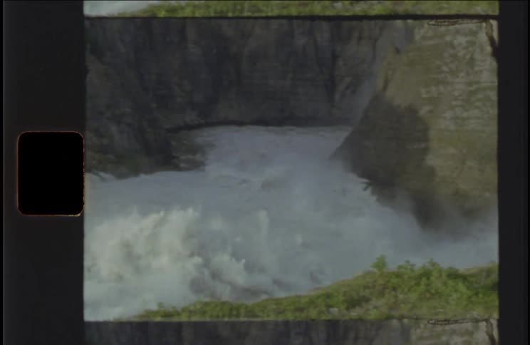 Powerful river rapids rush past rocky cliffs with mist