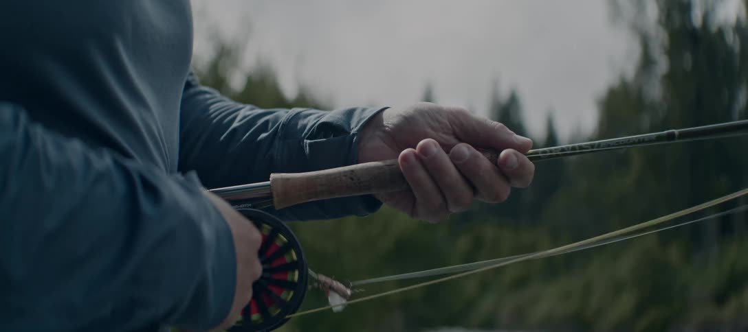 A person holds a fishing rod while fly fishing outdoors