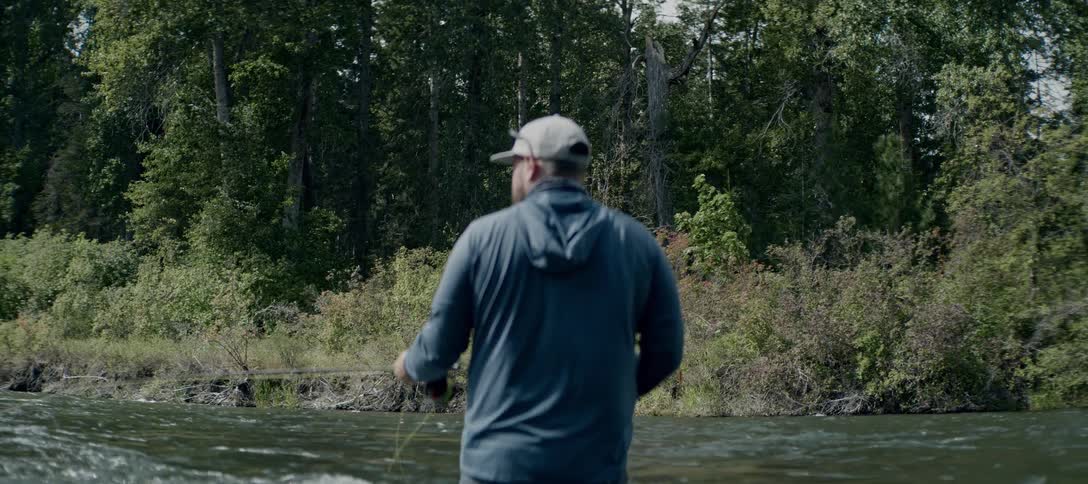 The man is fishing in the creek