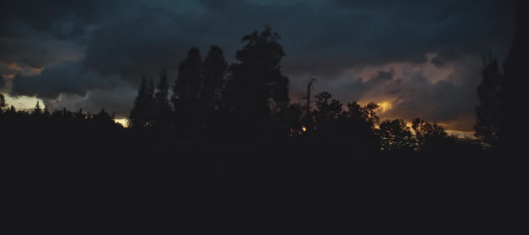 A barn and trees silhouetted against a sunset sky
