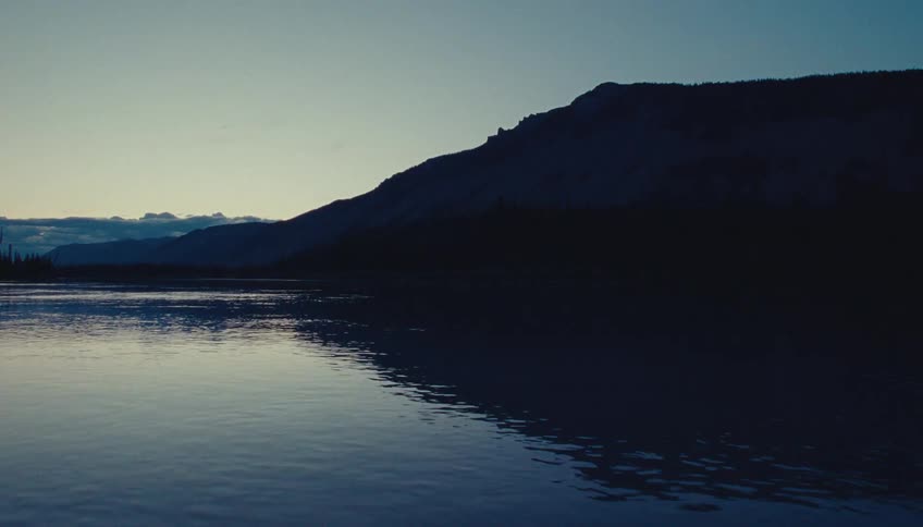 Reflective surface of a calm flowing water body at sunset