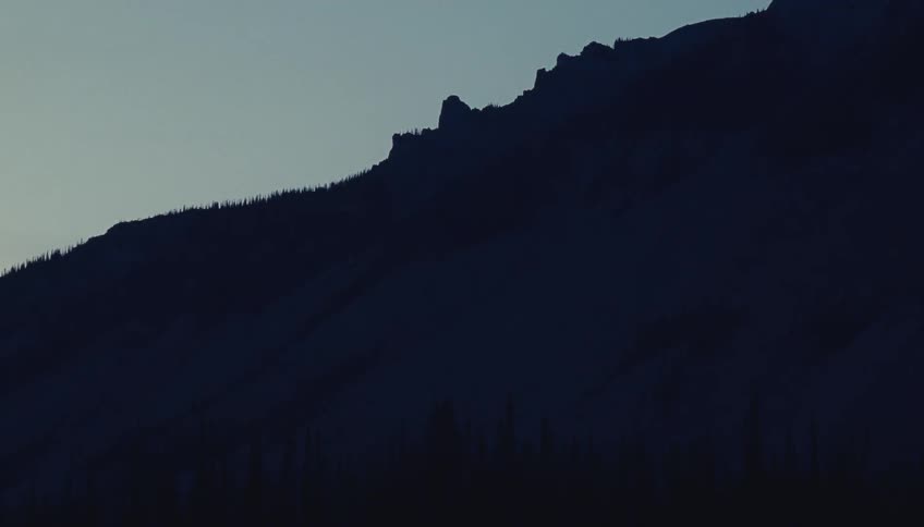 The tall mountain is covered in shade at sunrise