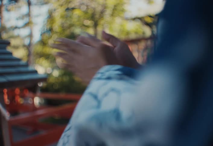 A persons hands come together in a clap in an outdoor setting