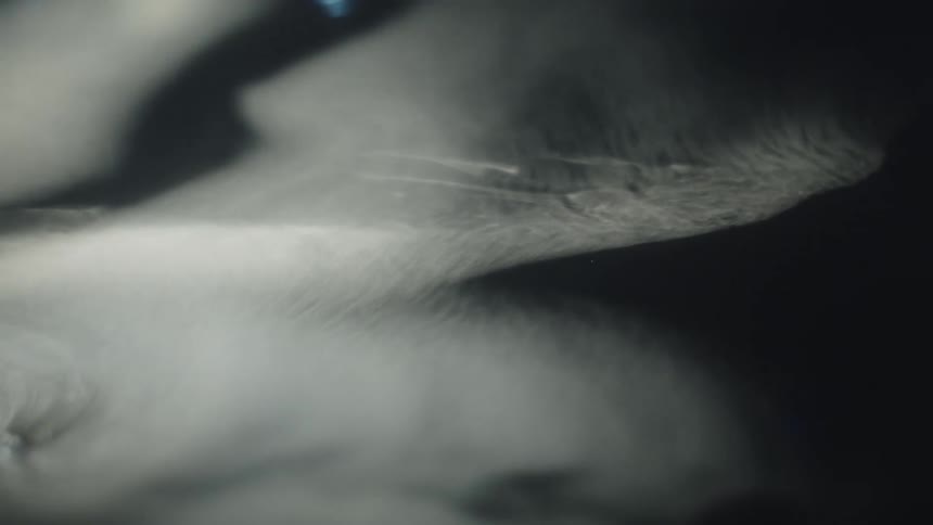 White smoke forming delicate shapes over a dark background