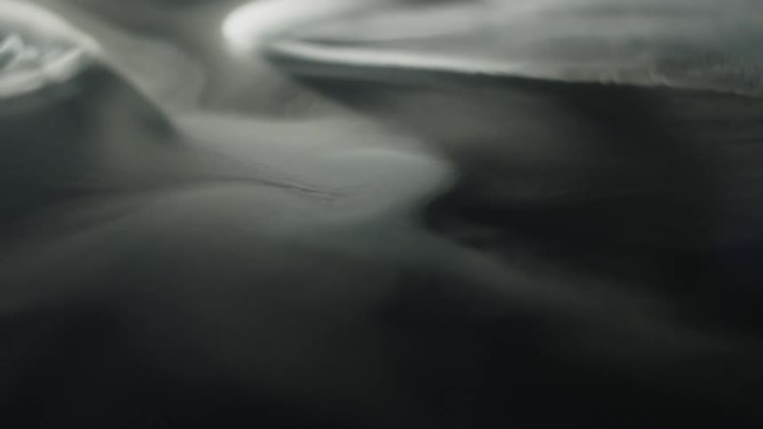 Whirls of white smoke drifting gently over a dark background