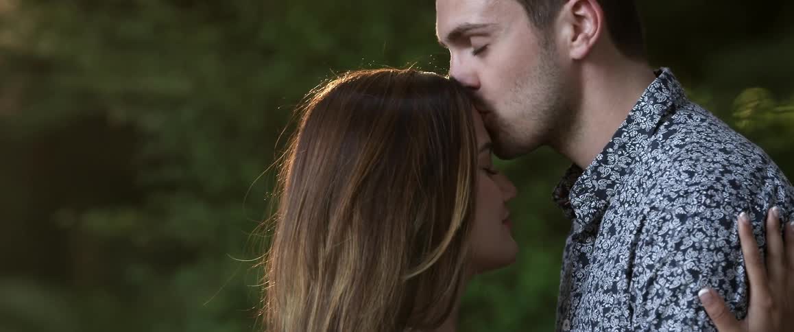 A man and woman laugh and kiss outside