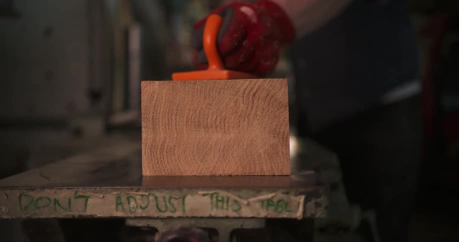 Wood block is pressed on the table with an orange handle during work