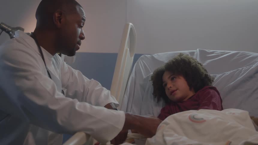 Doctor talking to a child lying in a hospital bed