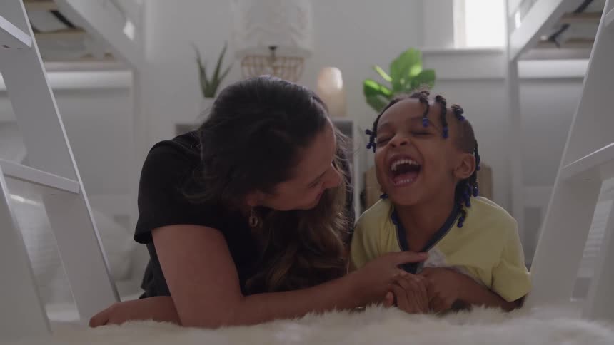 Woman and child lying on the rug laughing together