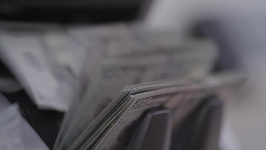 100 bills move aligned through counting machine with dark plastic components