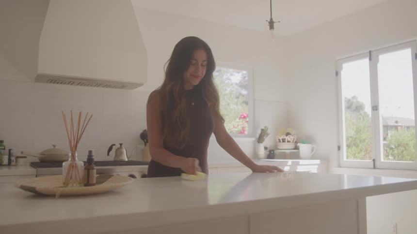 The woman cleans the counter and smiles
